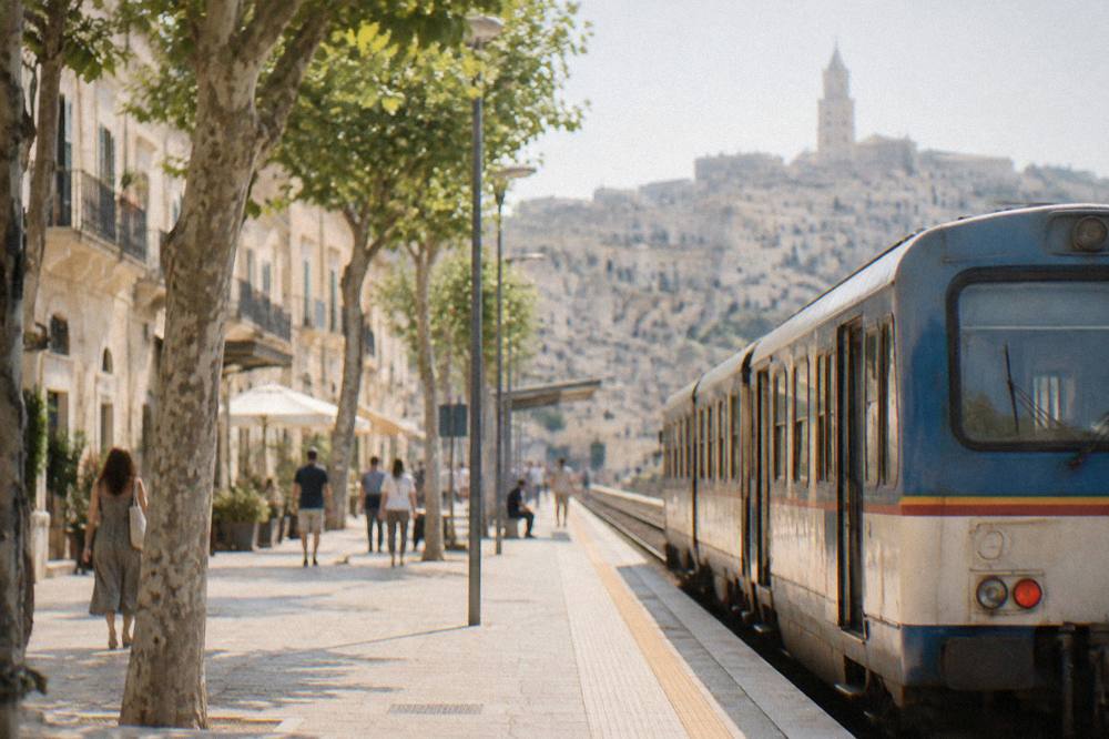 A small regional train waiting at a station platform in southern Italy