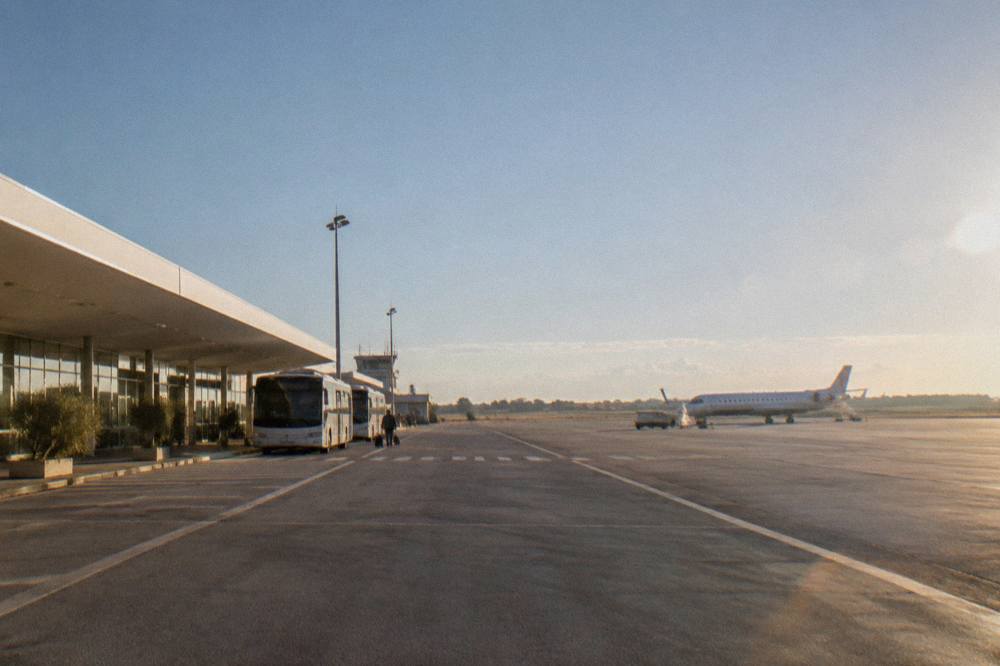 A small regional airport terminal building with parked aircraft on a clear morning