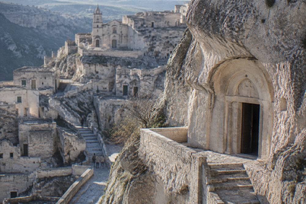 A rock-hewn church doorway carved into pale tufa stone in the Sassi of Matera