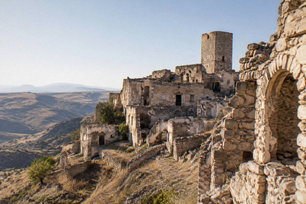 The abandoned stone buildings of the ghost town of Craco on a hilltop under a wide sky