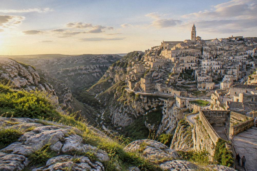 Panorama of the Sassi of Matera seen from the Murgia plateau across the Gravina canyon at dusk