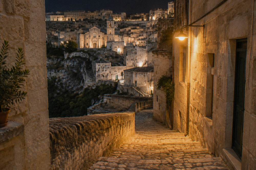 A narrow stepped stone lane in the Sassi lit by a single warm street lamp at night