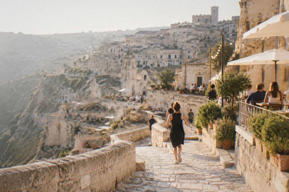 Warm lit terraces of stone houses at dusk with people at outdoor tables in early autumn