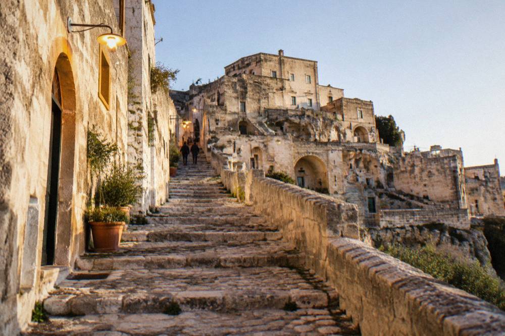 Stepped stone lane in Sasso Barisano lit by warm lamps in the evening