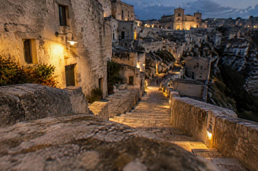 Lit stone stairway between cave houses in the Sassi of Matera at night