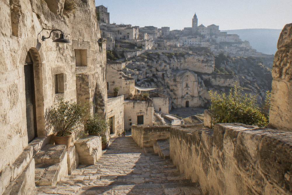 A stone staircase descending between cave hotel facades in the Sassi of Matera