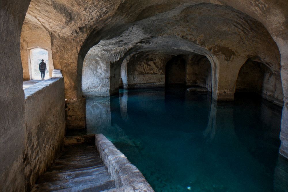 A vast vaulted underground water cistern with a stone staircase descending into it