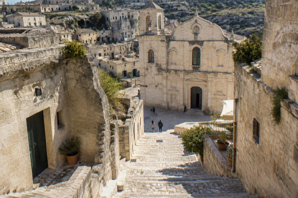 Stone stairway descending between cave dwellings toward a church entrance in Matera