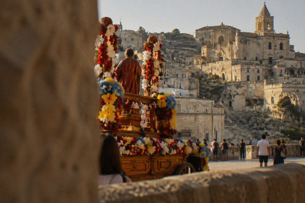 A triumphal float decorated with paper flowers standing in a Matera square during a summer festival