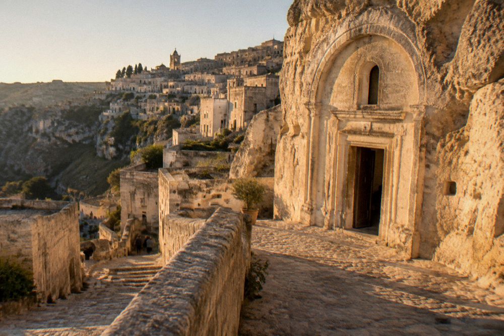 Stone facade of a rock-cut church in Matera lit by late afternoon sun