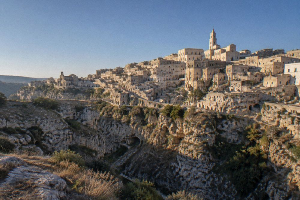 The illuminated Sassi districts seen from across the Gravina canyon under a deep blue evening sky
