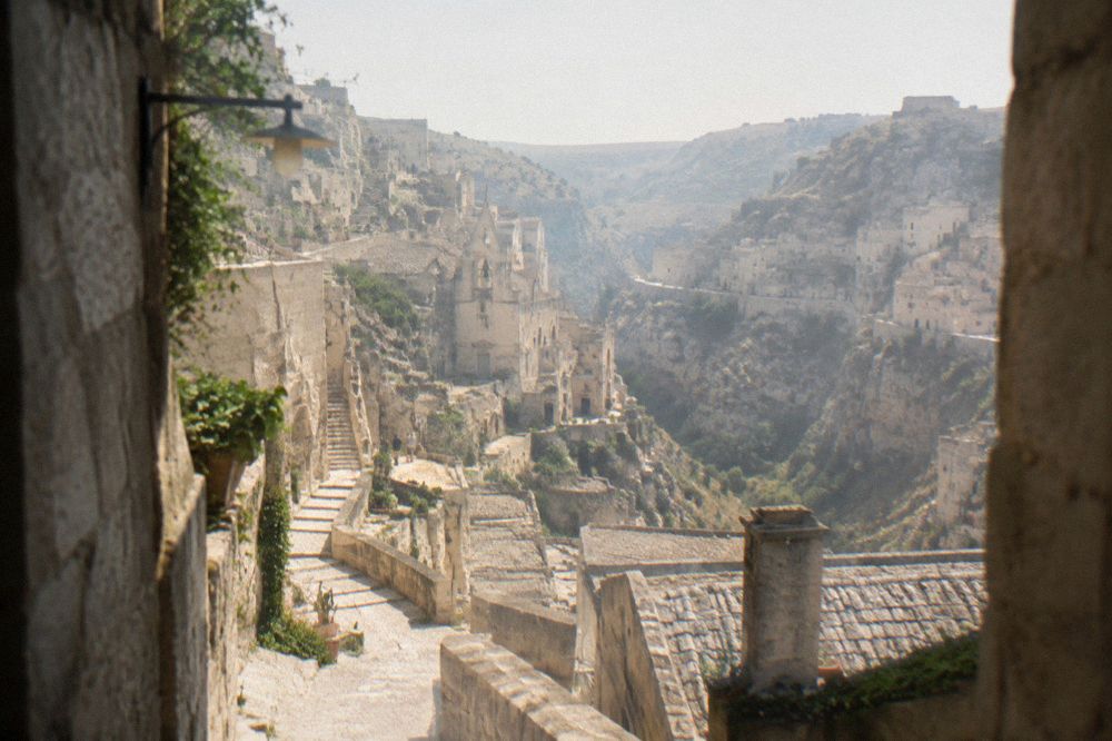 Stone stairways and cave-house facades stacked along the canyon side in Matera