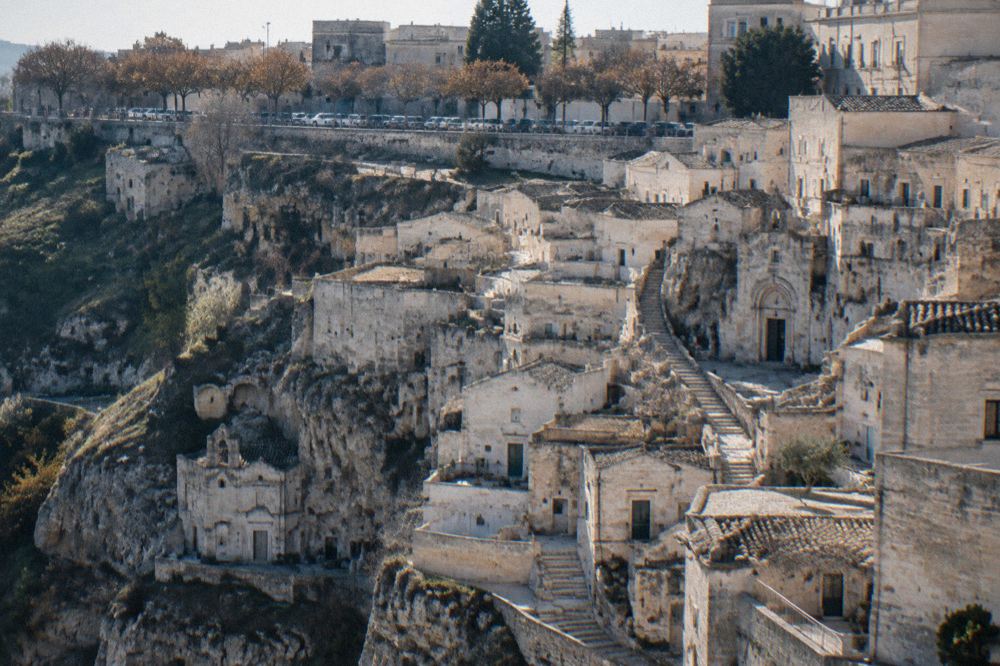 Cars parked along a tree-lined street on the modern plateau above the Sassi of Matera