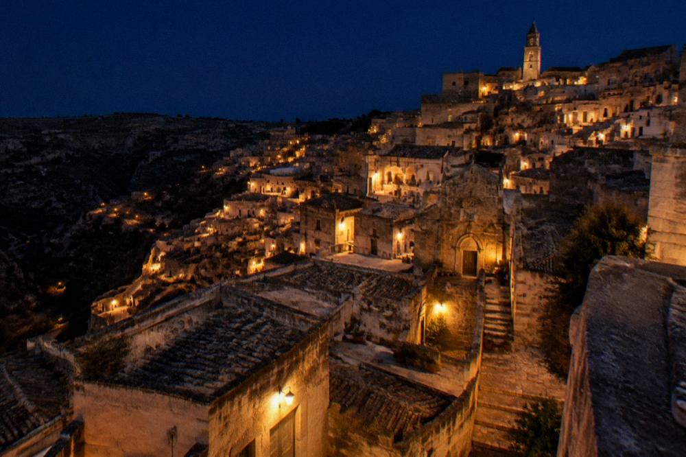 Sassi skyline at blue hour with warm lamps lighting the terraced stone facades