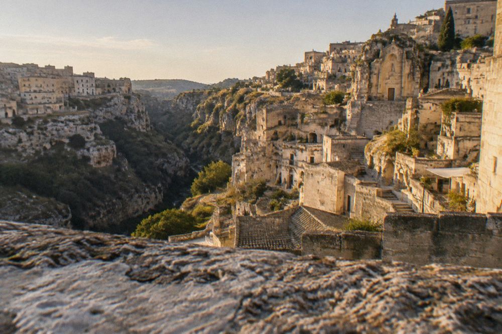 Warm evening light on the stone facades and terraces of Matera seen from across the ravine