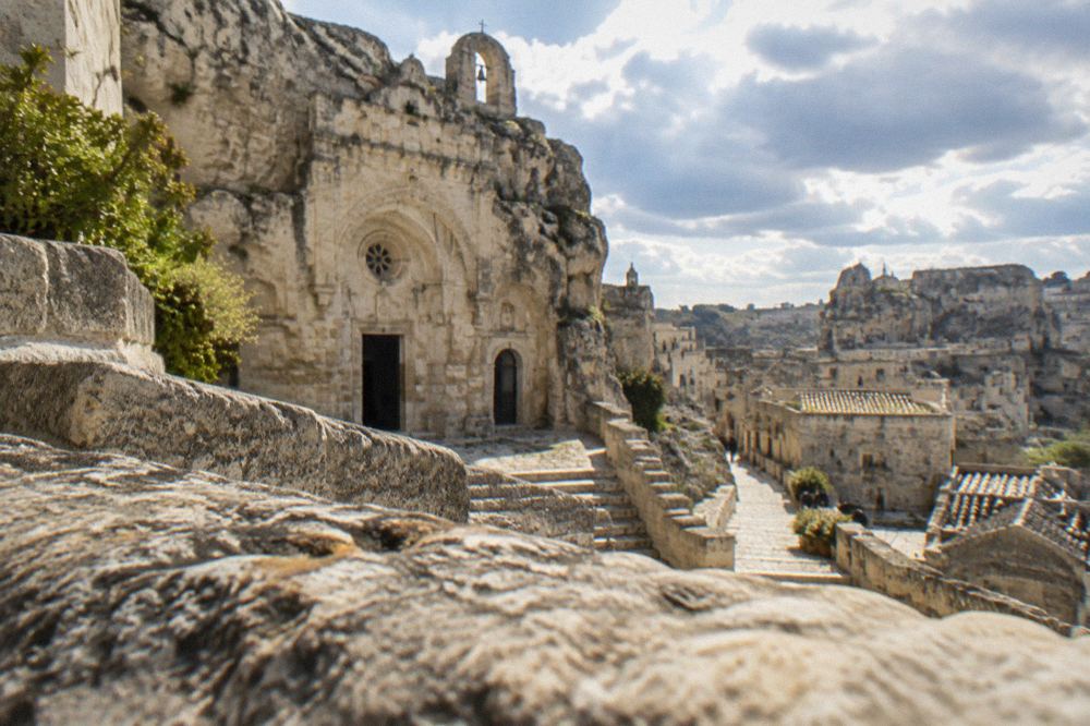 A rock-hewn church facade carved into pale limestone in the Sassi