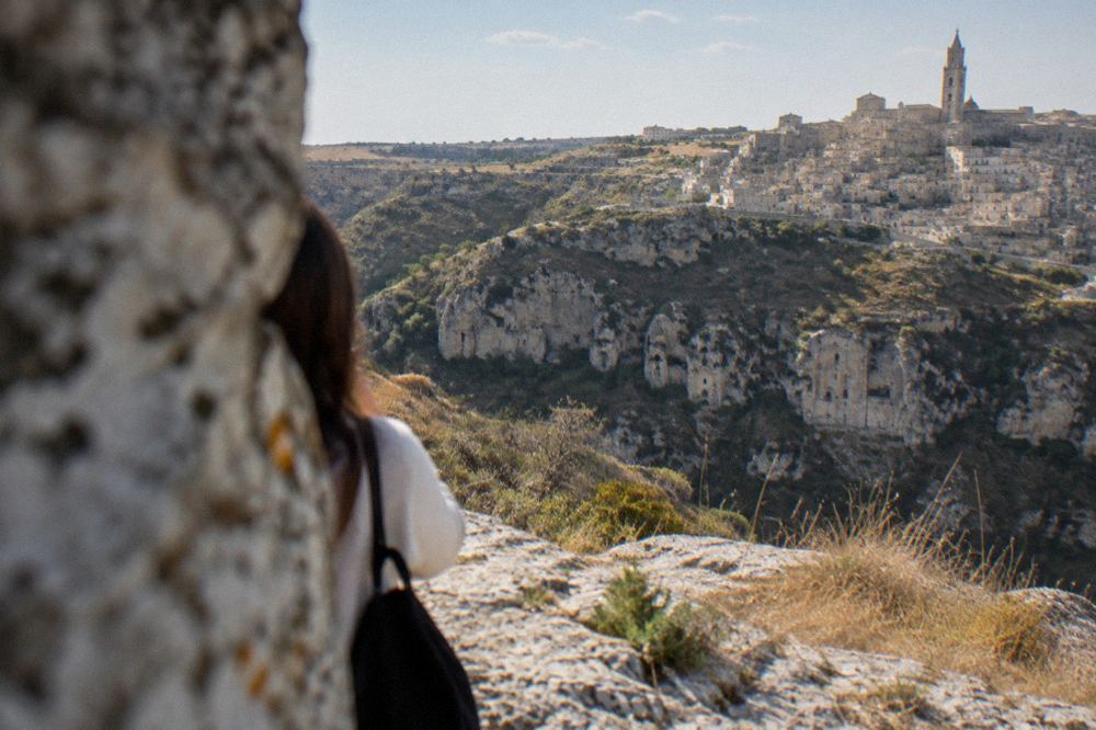 Rock-cut church facades carved into the tufa cliff face of the Gravina canyon opposite the Sassi