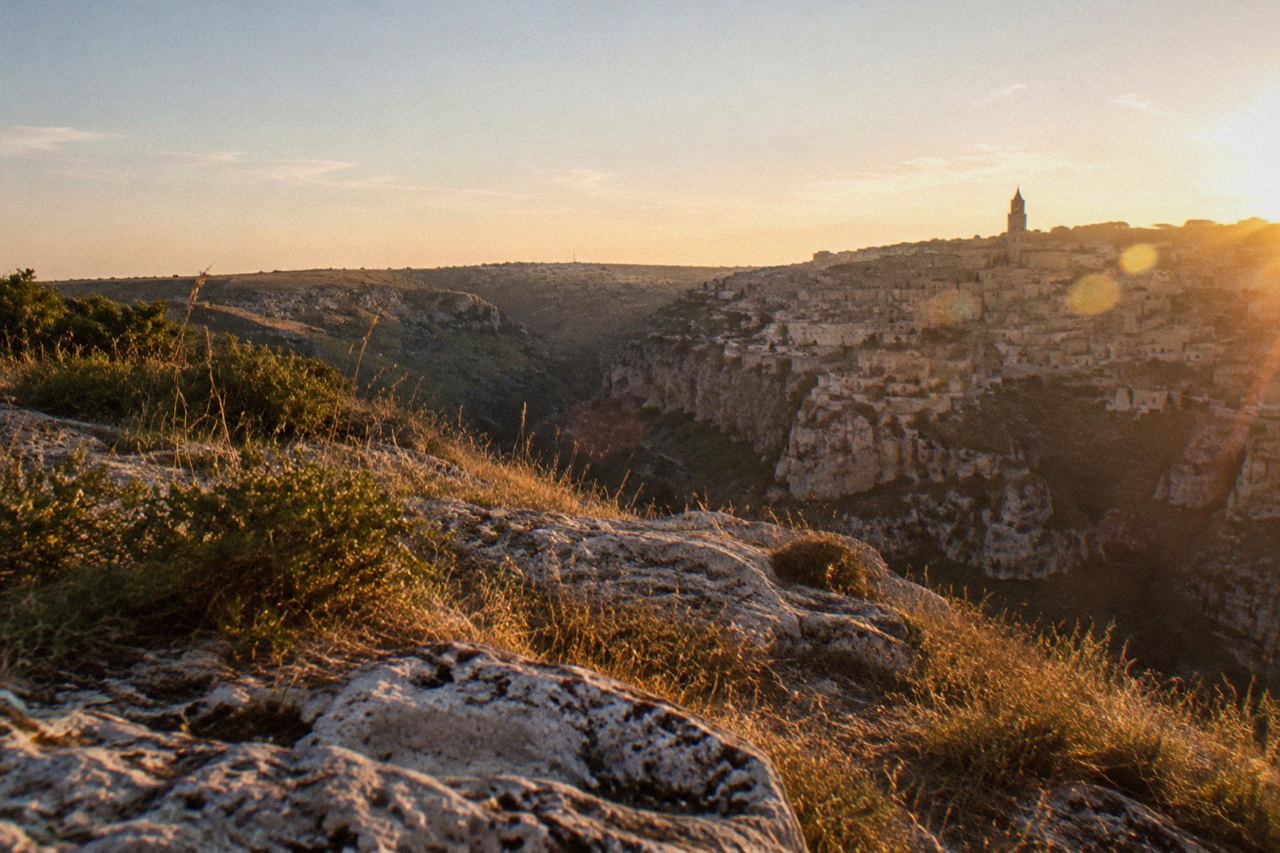 Pale stone cave dwellings of the Sassi rising above the Gravina canyon at golden hour
