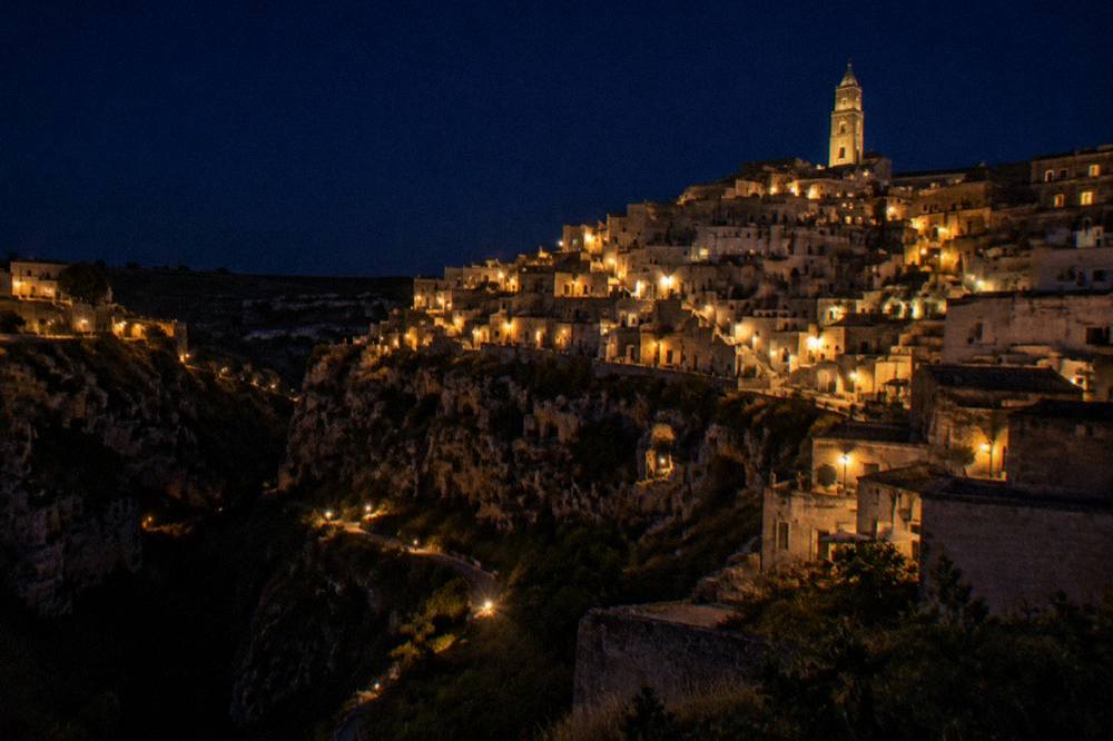 Illuminated Sassi rooftops seen from across the canyon after dark