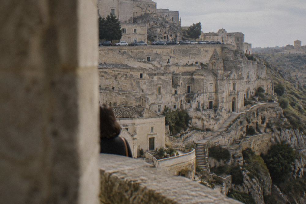Cars parked along a wide street on the plateau above the Sassi of Matera