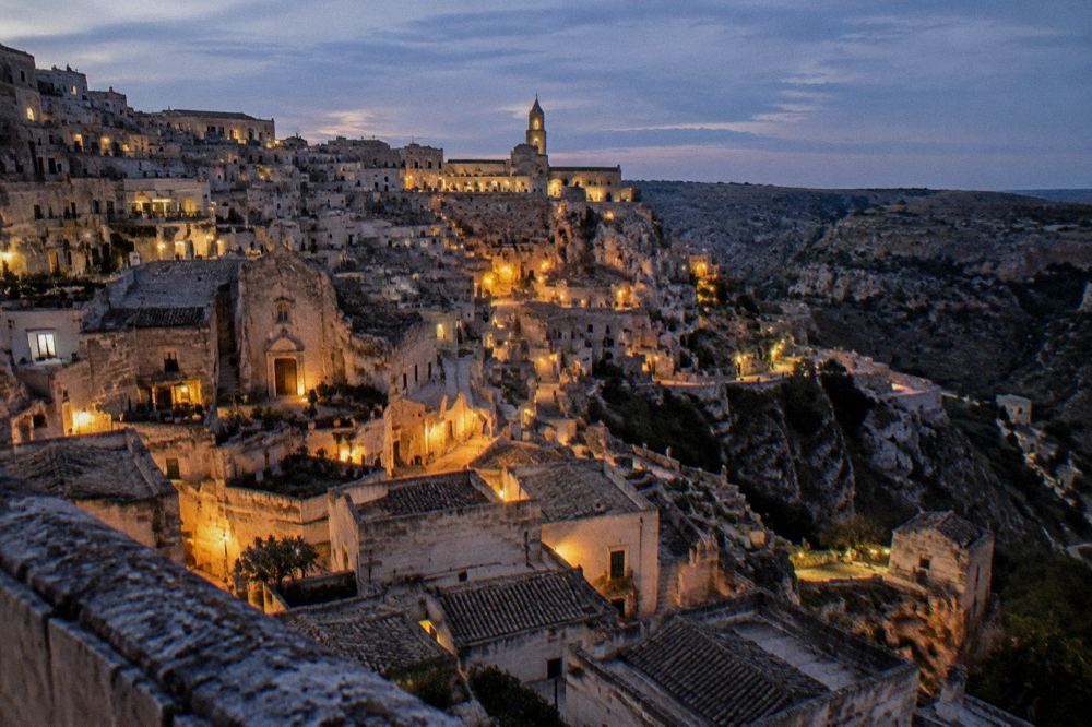 An evening view over the lit rooftops of the Sassi from a belvedere in Matera