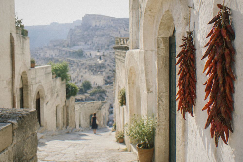 Strands of red peppers hanging to dry against a whitewashed wall in a southern Italian courtyard