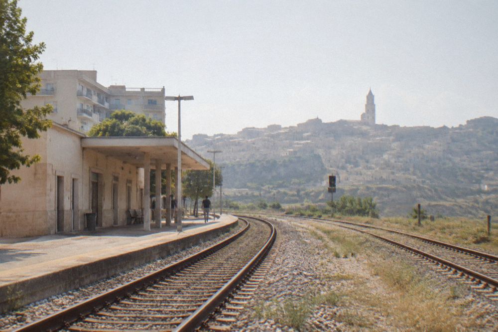 Railway tracks curving through open countryside towards a hilltop town in southern Italy
