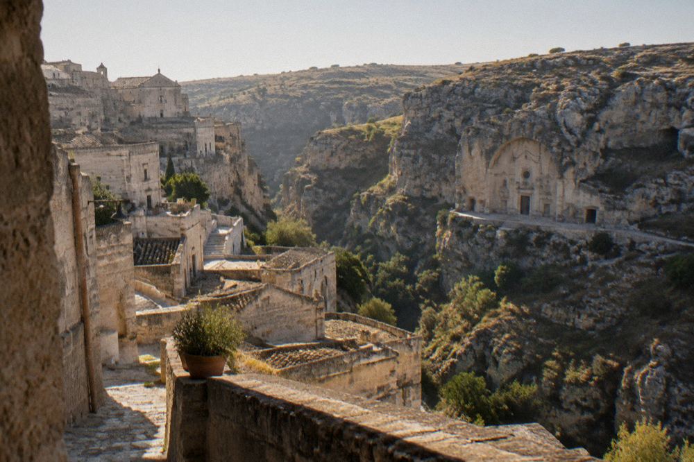 Rock-cut church facade carved into the canyon cliff opposite the Sassi of Matera at golden hour