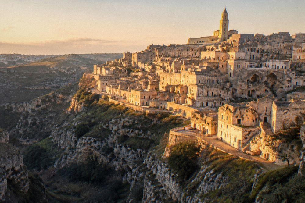 Illuminated cave terraces of the Sassi of Matera seen from across the Gravina canyon on a winter evening