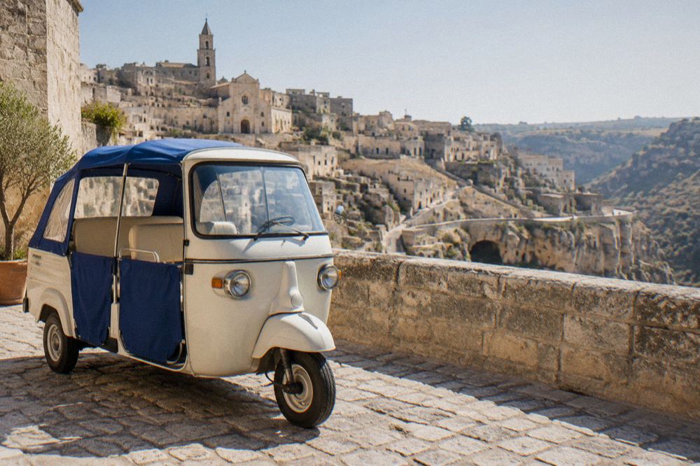 Three-wheeled Ape Calessino vehicle parked on a stone street overlooking the Sassi of Matera