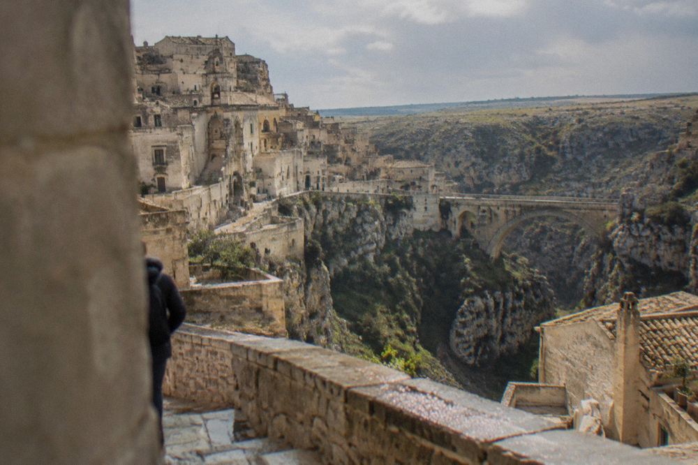 A deep limestone canyon with a stone footbridge crossing toward the flat Murgia plateau