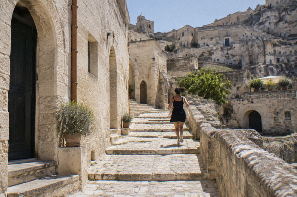 A narrow stepped lane between restored stone facades and cave doorways in Sasso Barisano