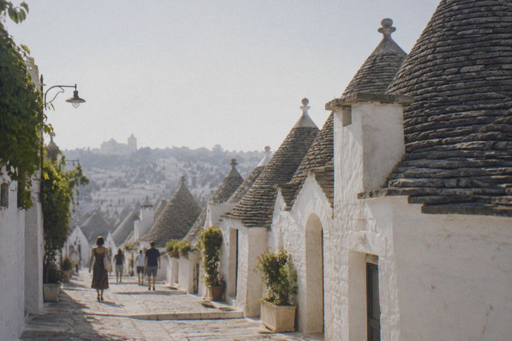 Whitewashed trulli houses with conical stone roofs in Alberobello seen from a side street
