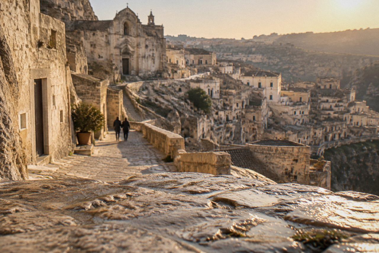 A stone road winding through the ancient cave dwellings of the Sassi districts in Matera at golden hour