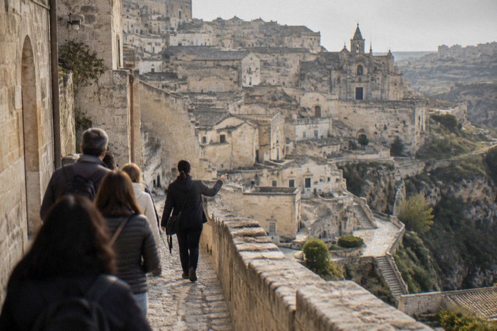 A guide leading a small group along a stone street in the Sassi of Matera