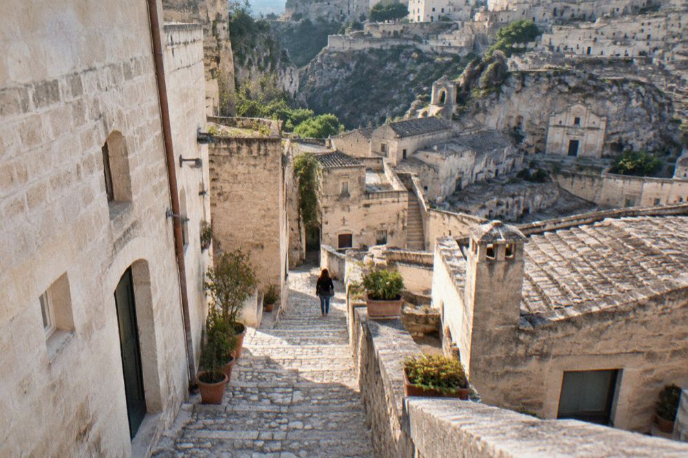 A narrow stone stairway between pale tufa buildings in the Sassi district of Matera