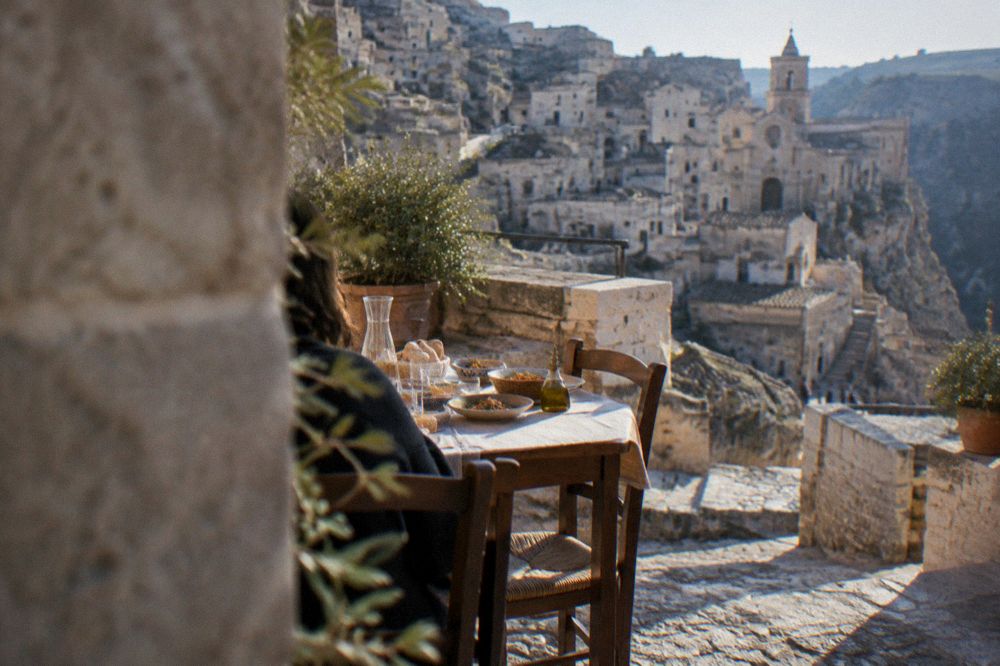 A table set with bread and local dishes outside a small restaurant in a stone lane in Matera