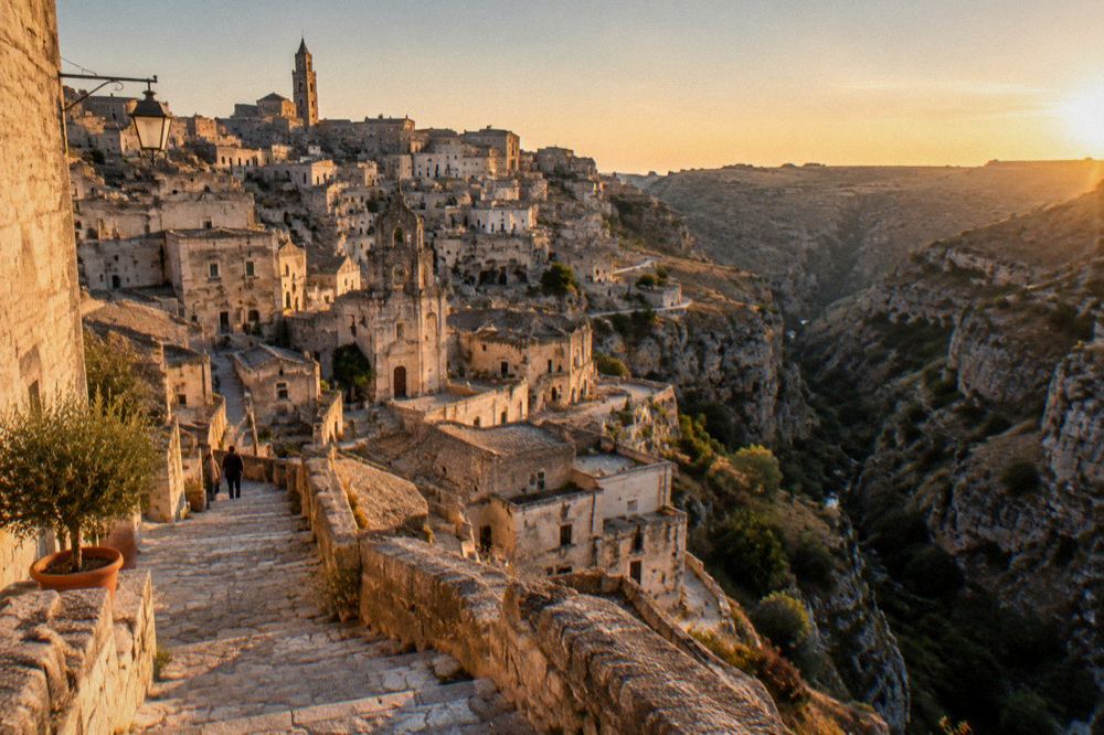 A wide view of the Sassi district and the canyon at dusk with warm light on the stone facades