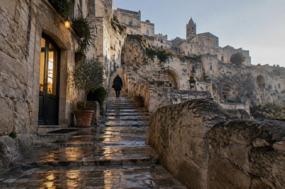 Glossy wet stone staircase between cave houses in Matera reflecting warm window light