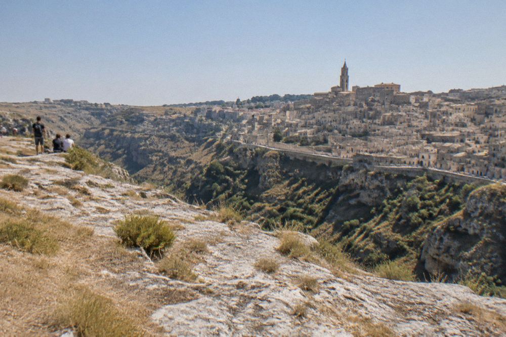 A wide view over the stacked stone rooftops of the Sassi from across the Gravina canyon
