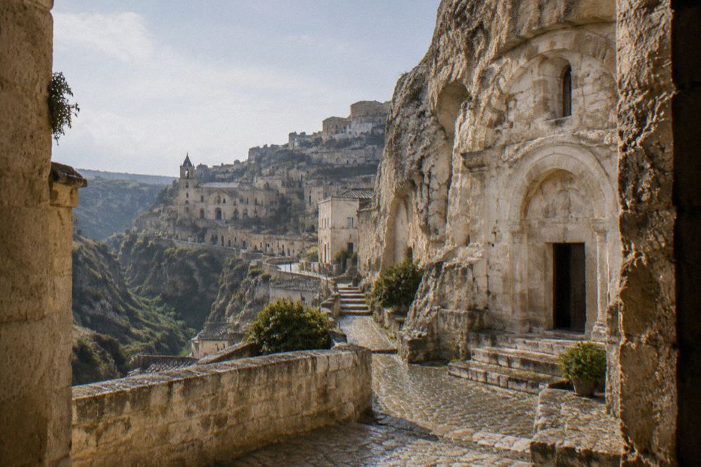 The rock-cut facade of a rupestrian church carved into pale tufa stone in Matera