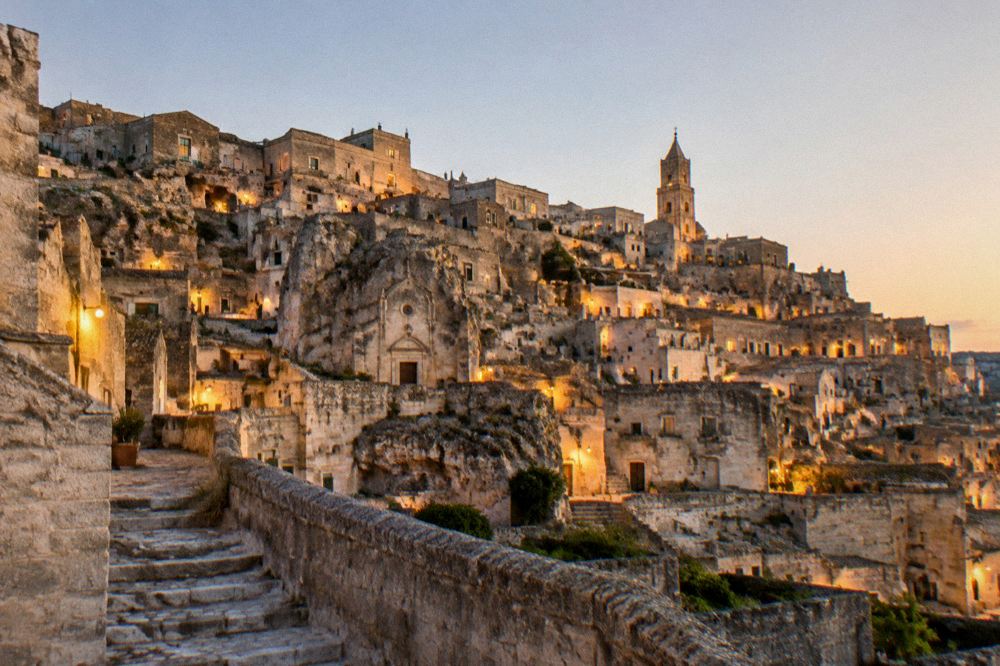 The illuminated Sassi of Matera seen at dusk with warm lights in the cave dwellings
