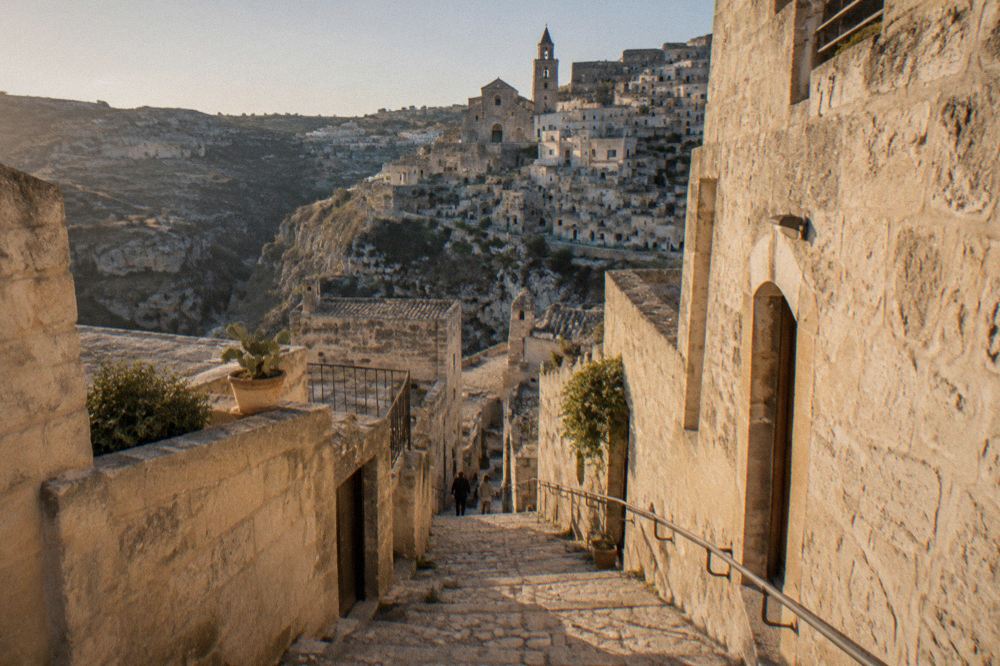 Stone stairway with handrail descending between pale tufa buildings in the Sassi