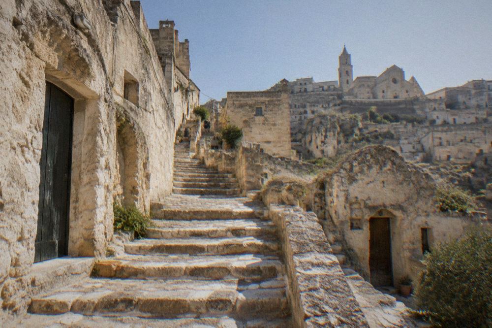 A stone staircase in the Sassi of Matera worn smooth, with cave doorways on either side