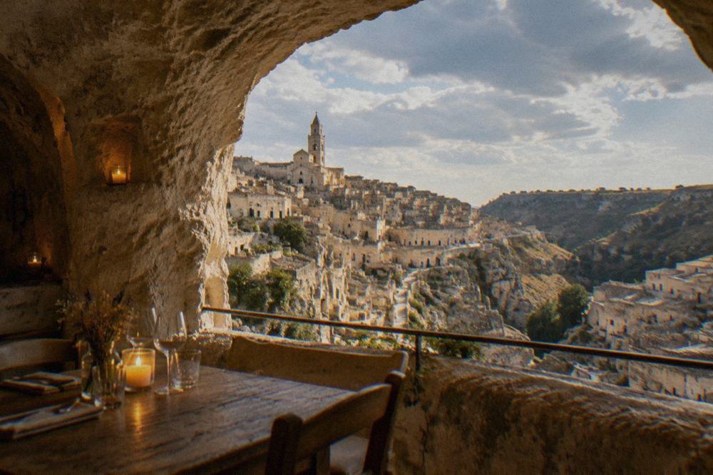 Rustic table set inside a candlelit cave restaurant in Matera with stone walls and arched ceiling