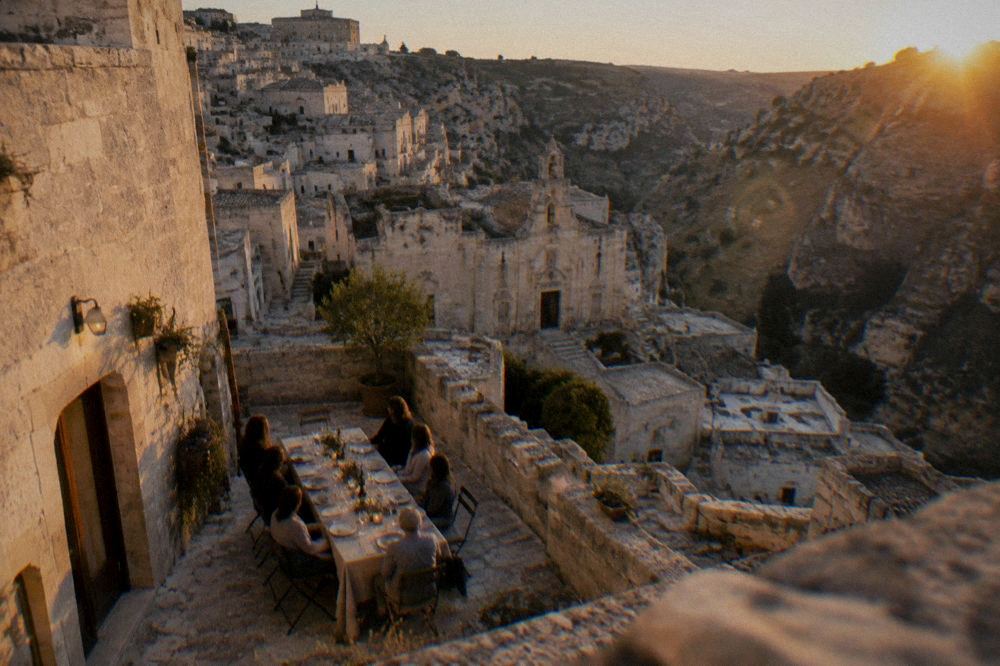 A long table set for dinner outside a stone building in the Sassi at dusk