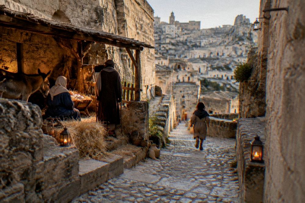 A candle-lit nativity scene in a stone alley of the Sassi during the living crib