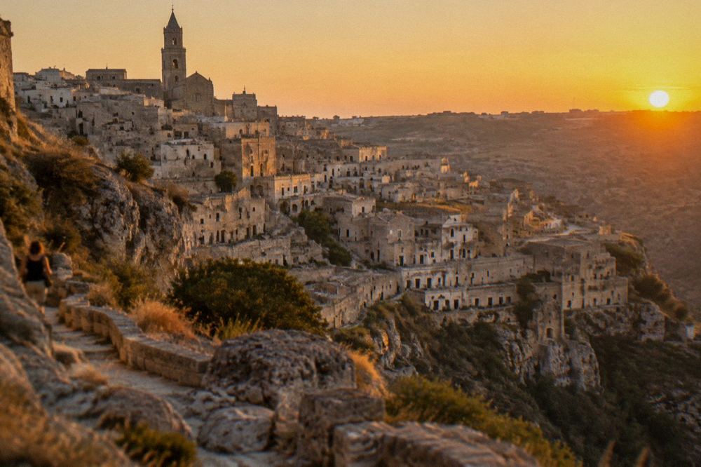 Sunset light on the cave city skyline seen from a rocky viewpoint path